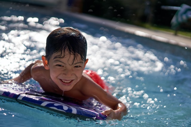 niño empleando la tabla en la piscina